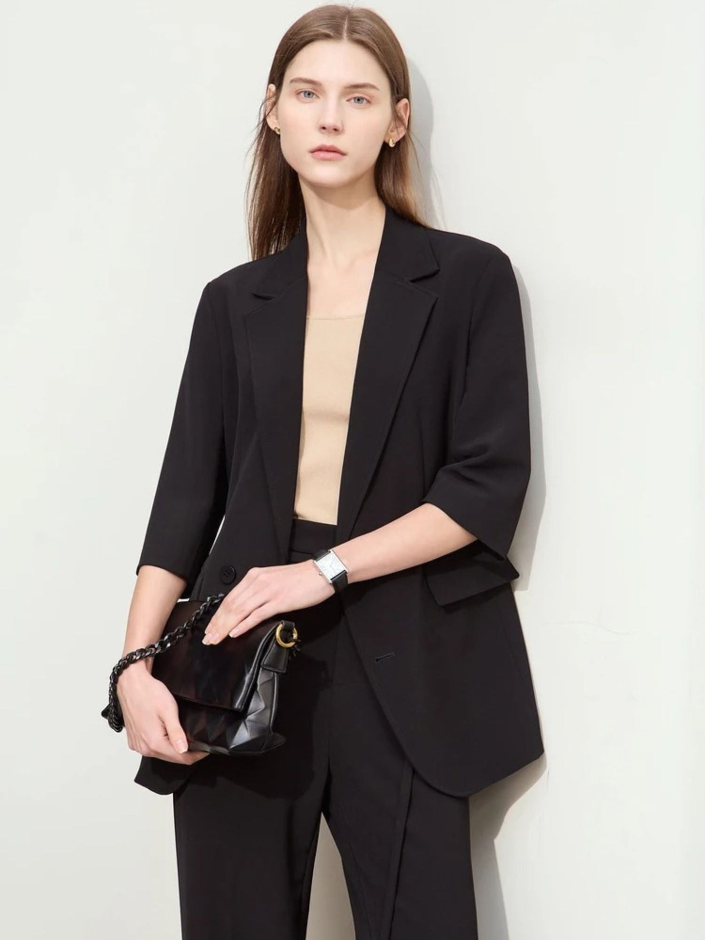 Schwarzer Hosenanzug mit 3/4-Arm-Blazer, Modell frontal mit Clutch.