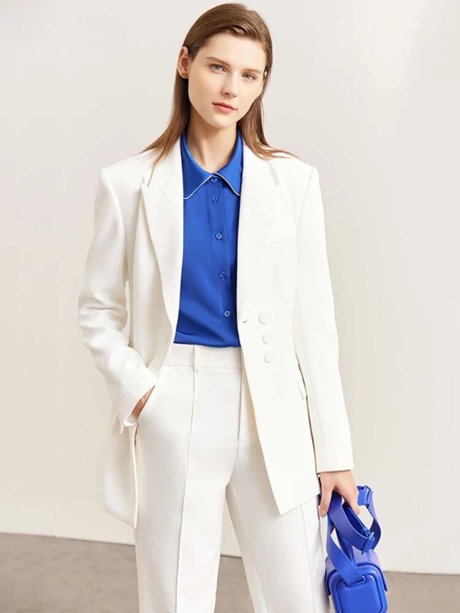 Weißer Damen-Blazer mit blauer Bluse, Modell frontal mit Tasche.