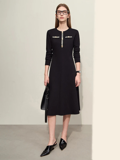 An elegant woman wearing a military inspired dress. The dress has long, fitted sleeves and an a-line silhouette. The bodice showcases a gold embroidery design with buttons. 