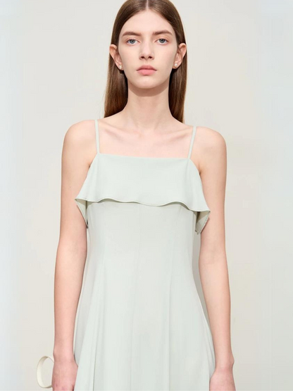 A brunette woman wearing a simple and minimalist chiffon dress in mint green.