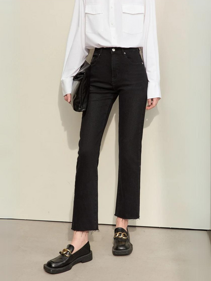 A woman wearing a classic white long sleeve shirt with a pair of black, pencil cut jeans and a pair of loafers.